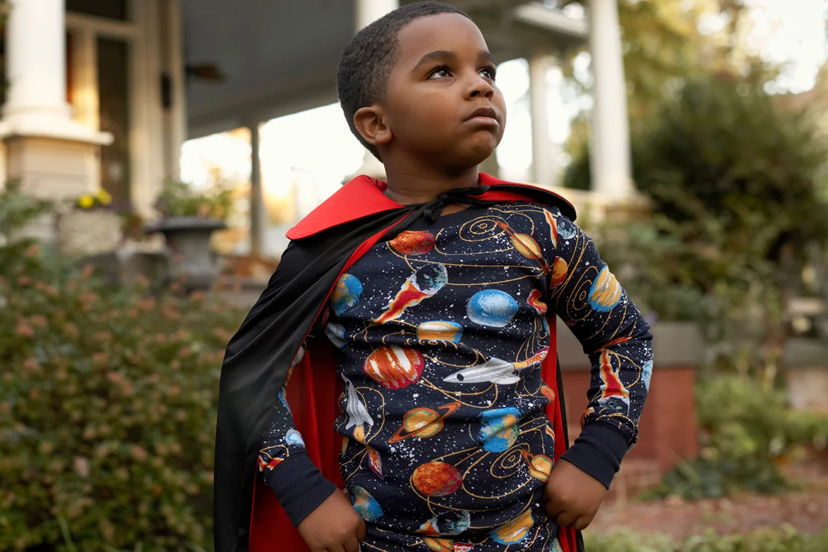 Boy (6-7) wearing costume standing outdoors