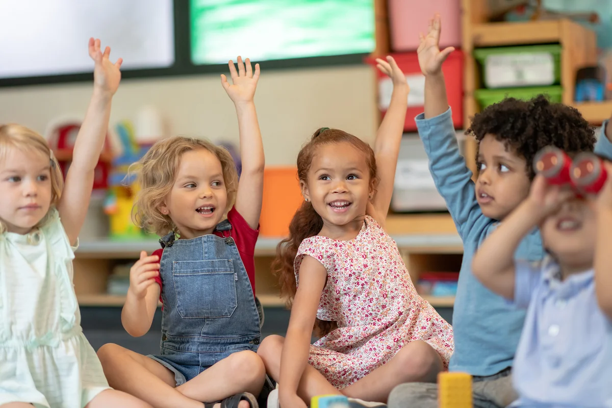 preschool students is sitting with their legs crossed on the floor in their classroom