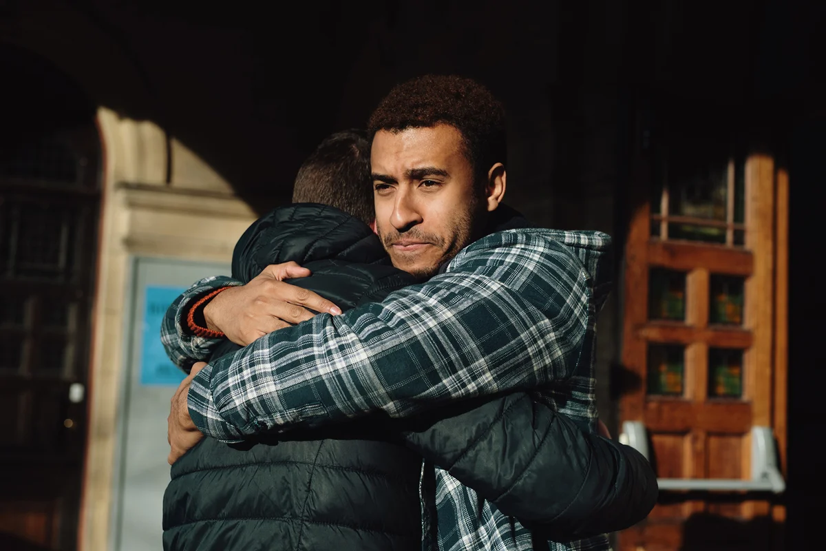 Two men hug outside of a building