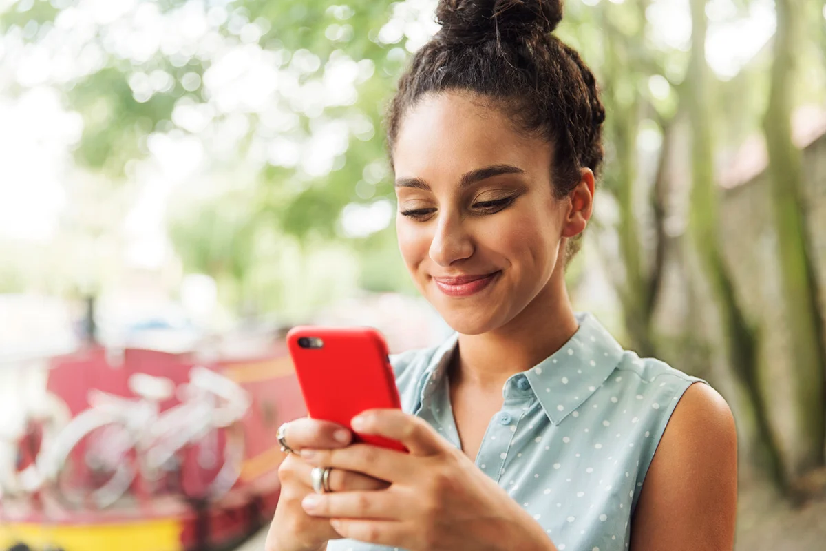 Woman using smart phone next to river.