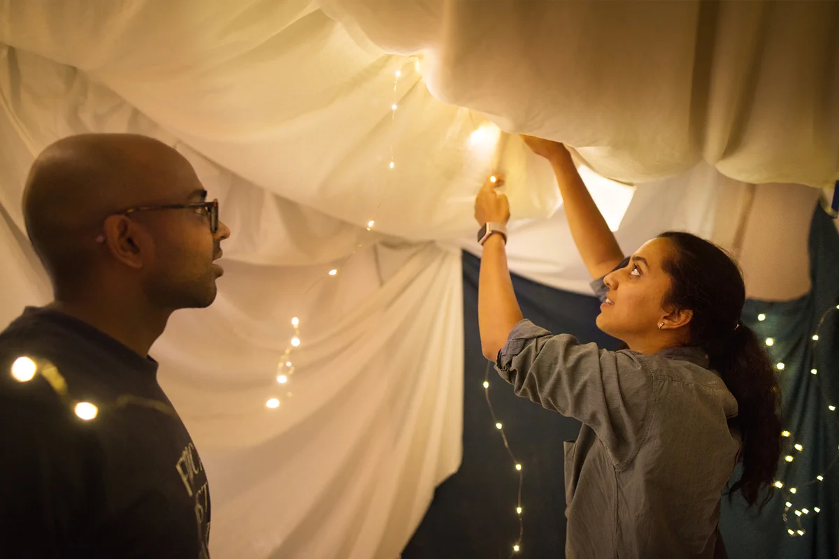 Shot of a couple adding lights to a tent made in their living room