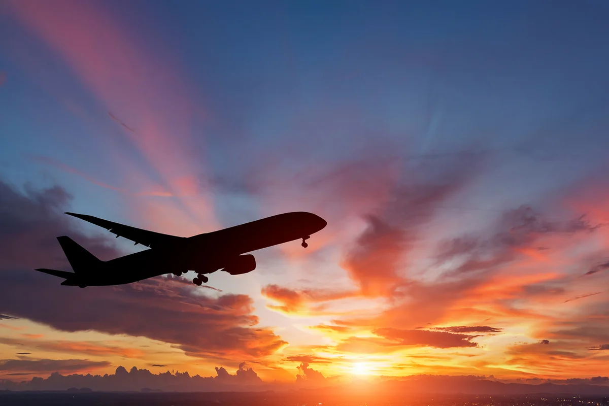 The silhouette of a passenger plane flying in sunset