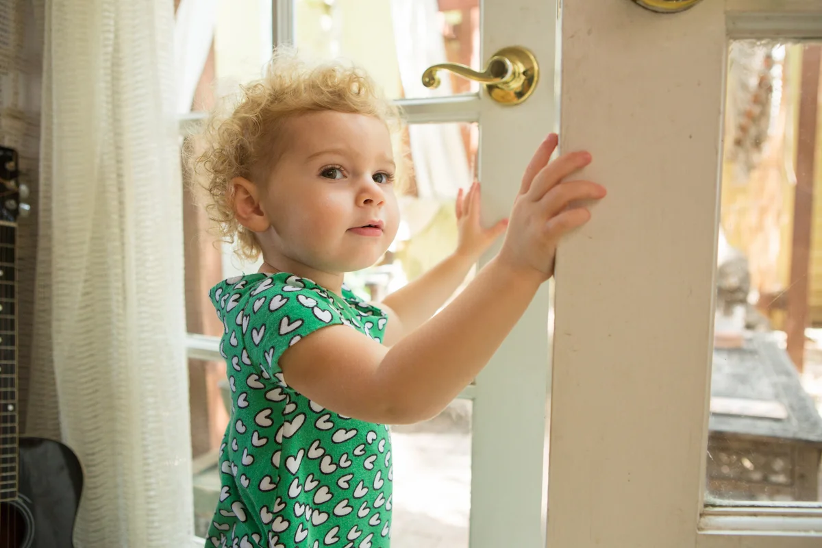 toddler girl trying to open door