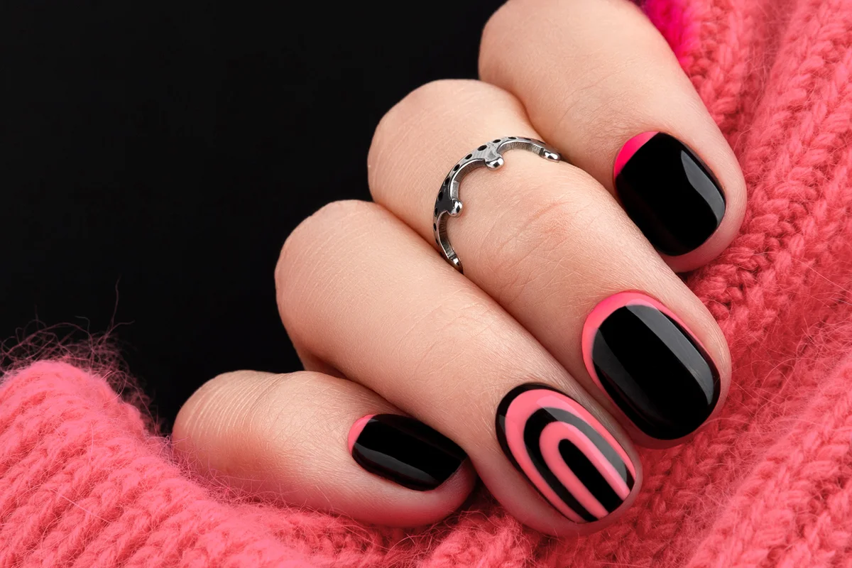 Womans hands with trendy pink and black manicure