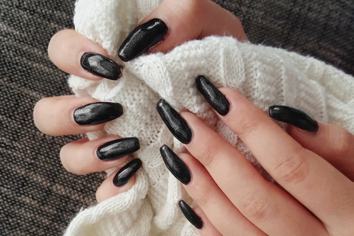 Close-up of hand with black nail varnish holding wool