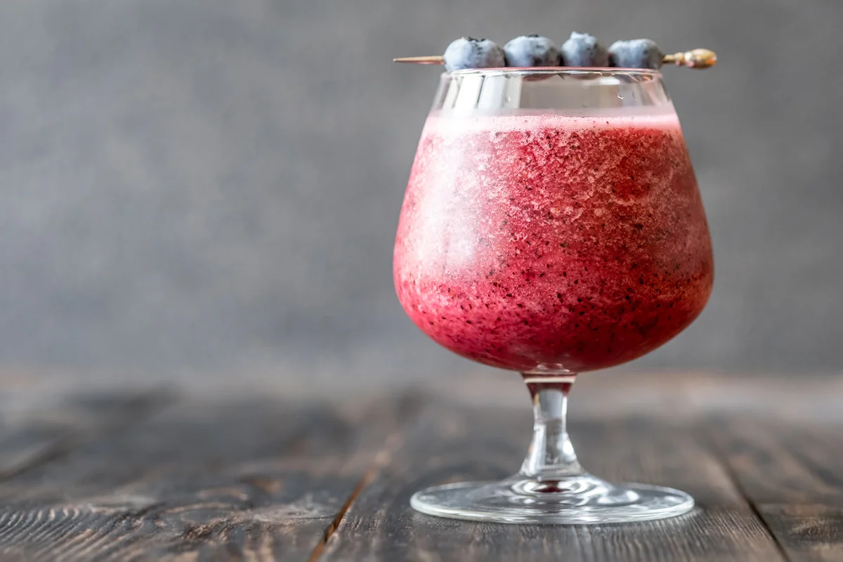 Glass of blueberry daiquiri cocktail garnished with berries