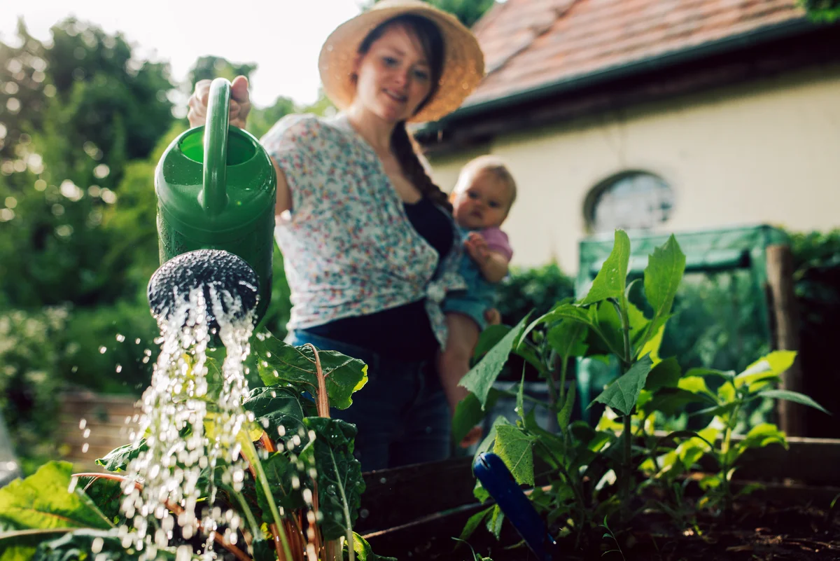 woman and baby watering veggies
