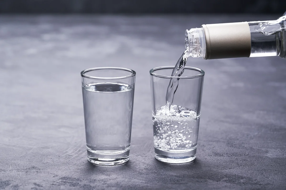 Vodka from the bottle is poured into a glass
