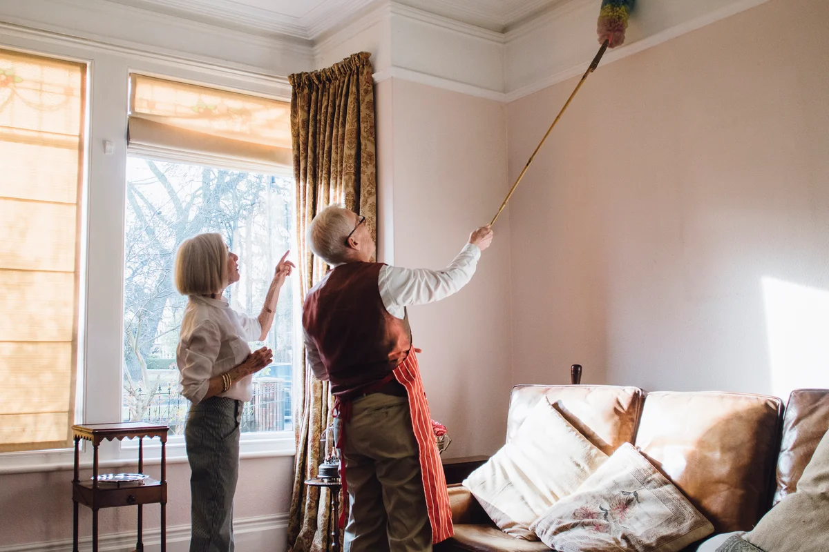 Man dusting a high ceiling