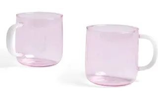 Two transparent pink borosilicate glass mugs with opaque white handles on a white background.