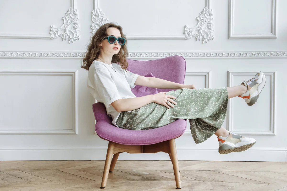 Young fashionable woman model posing sitting on an armchair