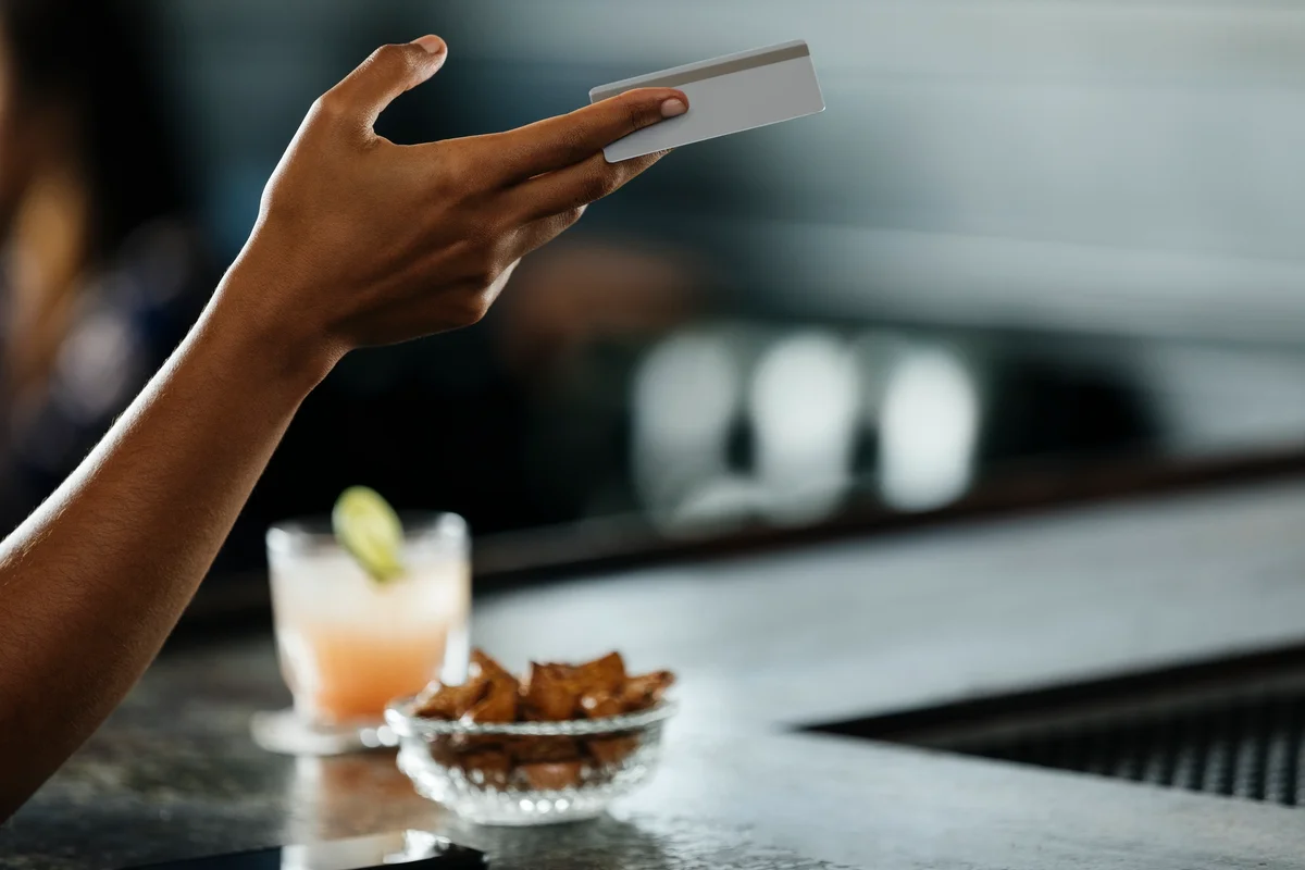 person handing over a credit card at a bar