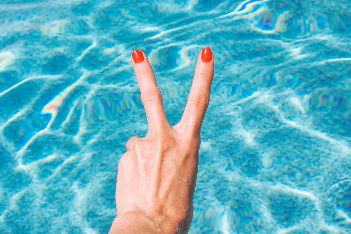 Woman's hand gesturing peace sign with red nails