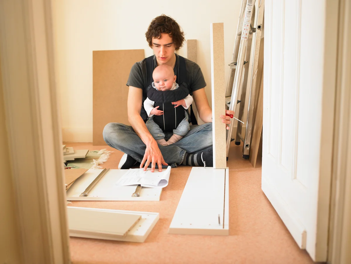Man with baby assembling particle board furniture