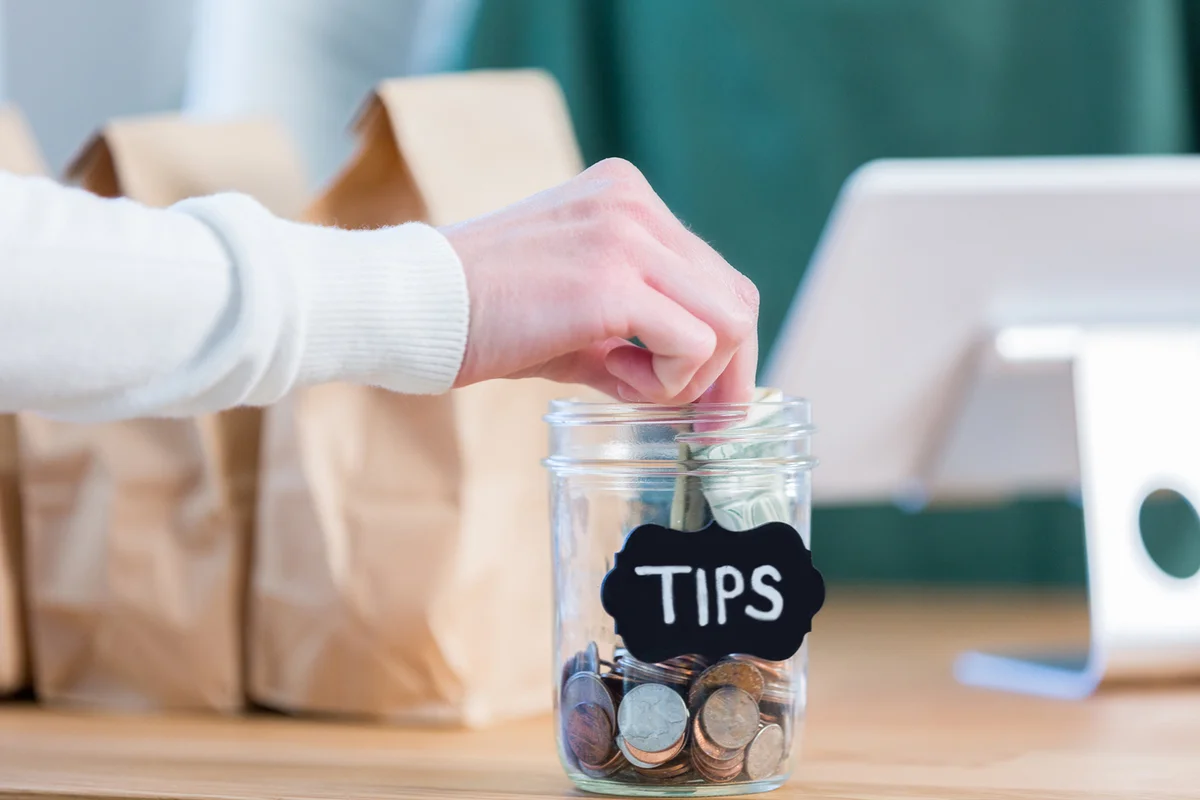 coffee shop customer adds to a tips jar