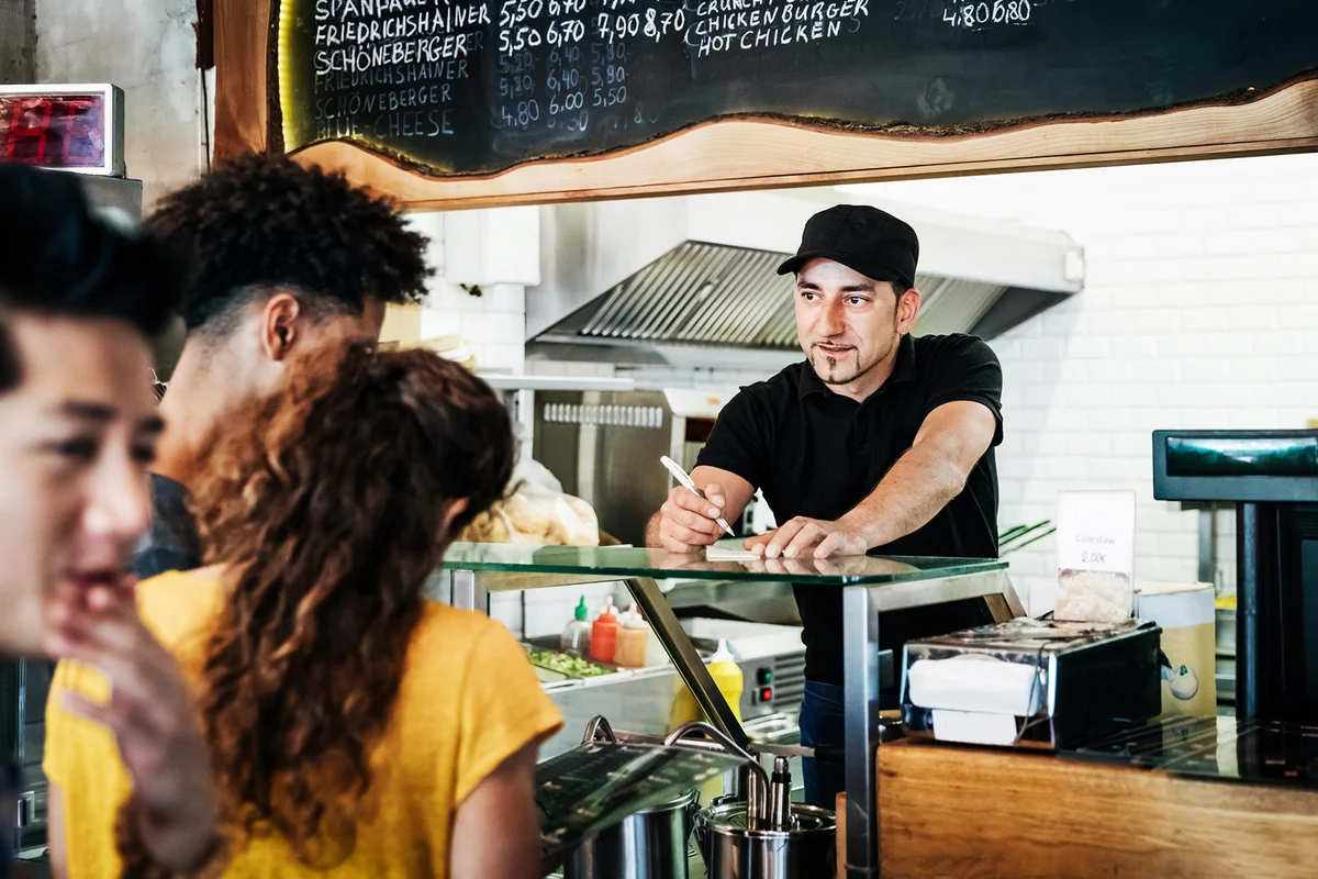 A waiter is taking some orders from his customer