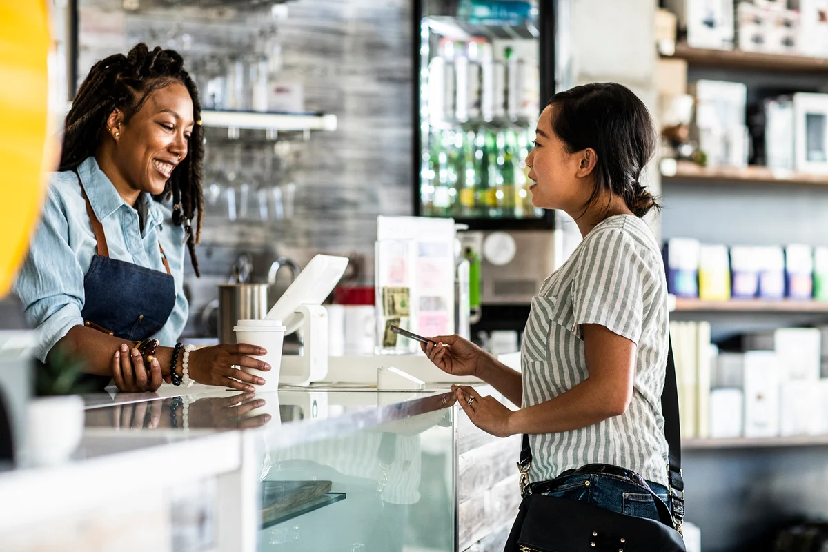 Young woman paying for coffee with credit card