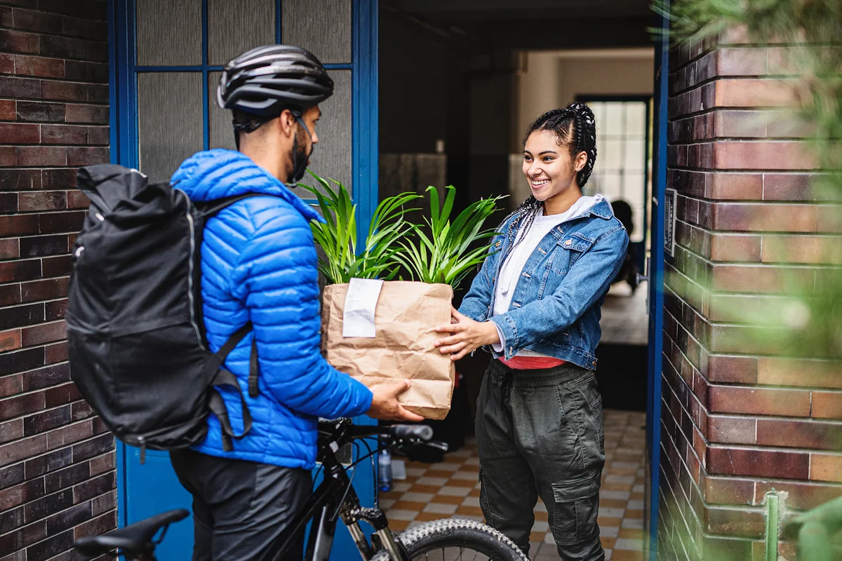 Delivery person giving paper bag to customer