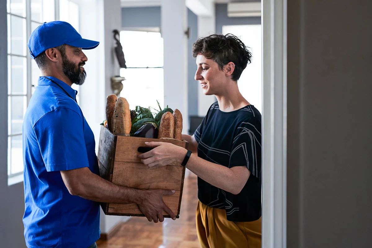 Woman receiving groceries from delivery person
