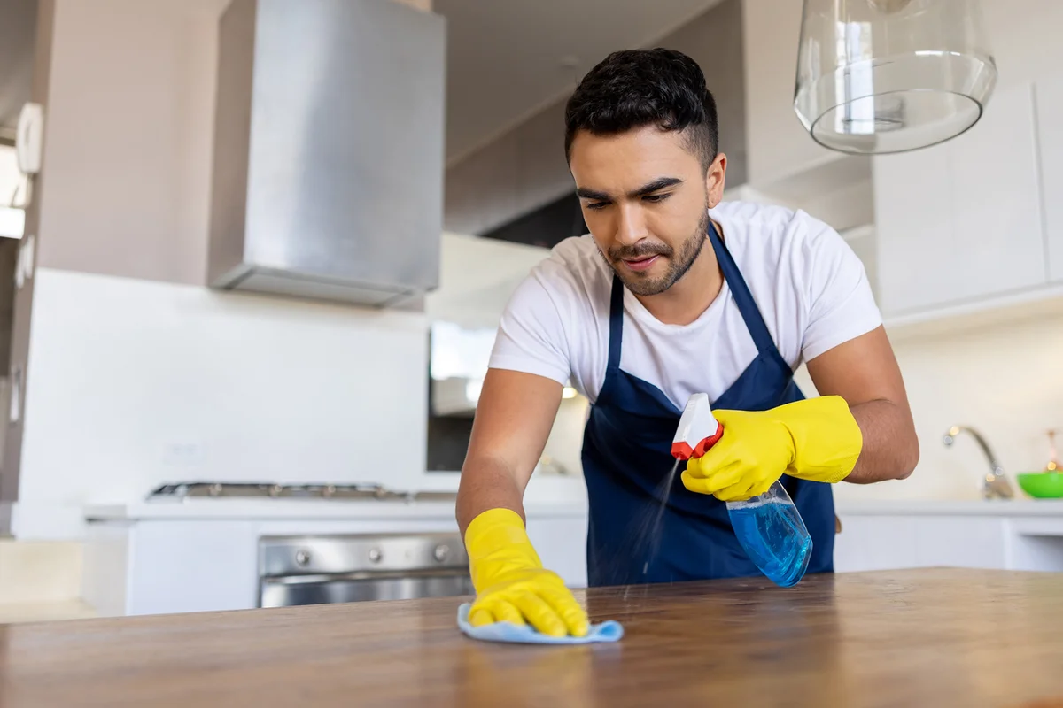 Professional cleaner cleaning a table while working at a house