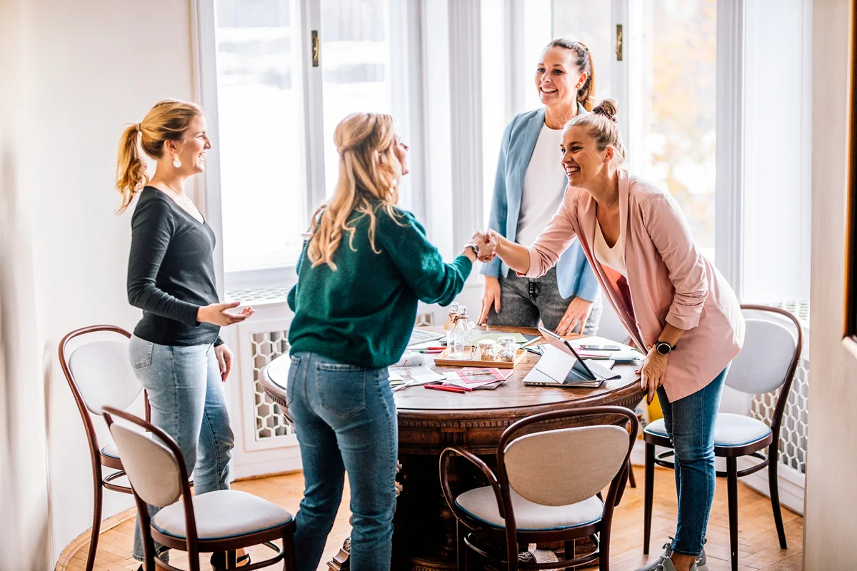 Smiling female professionals greeting each other