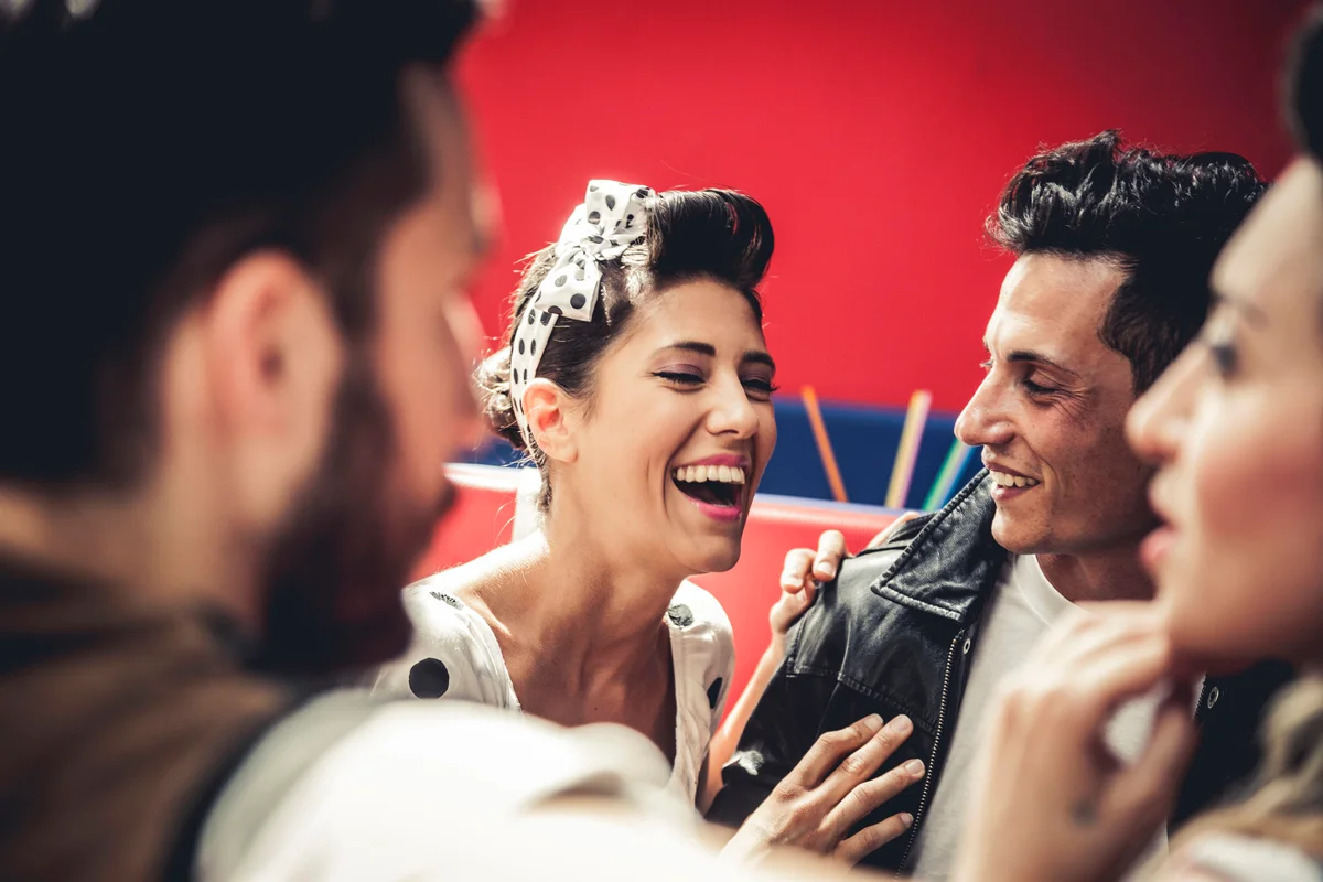 Friends dressed in 50s style have fun in a dinner