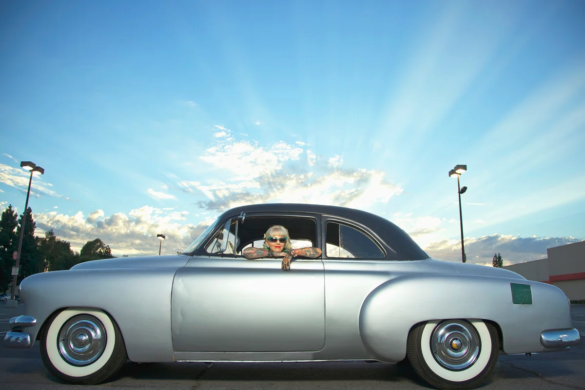 Woman with tattoos leaning out window of 1951 Chevy