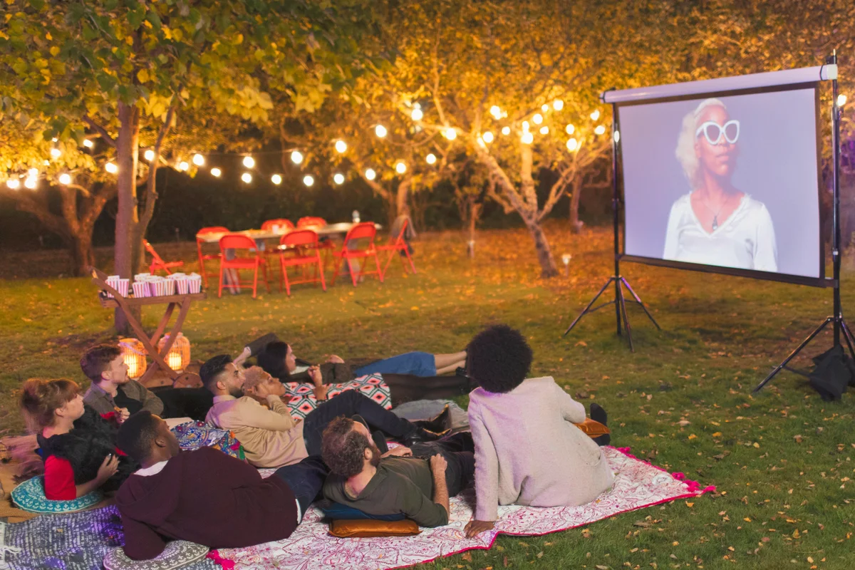 Friends watching movie on projection screen in backyard