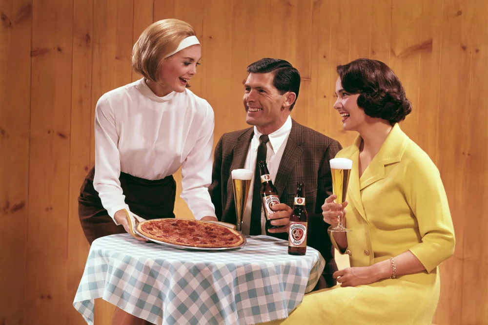 Two women and a man enjoying a pizza and some Ballantine beer, ca. 1950s