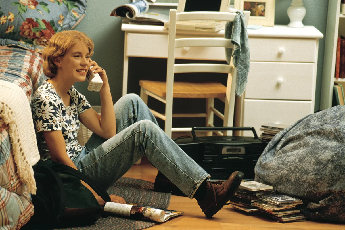 90s photo of teen girl sitting on floor in room on telephone