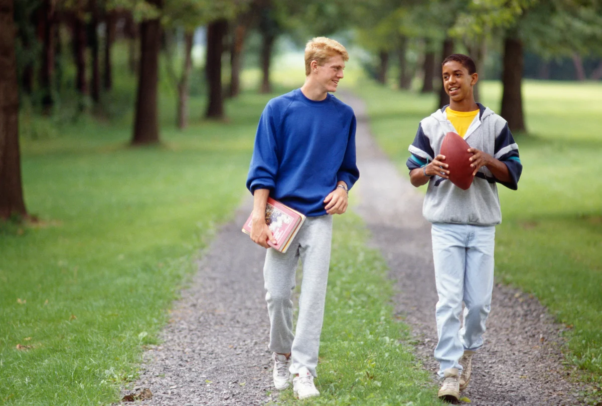 two teen boys walking with a football