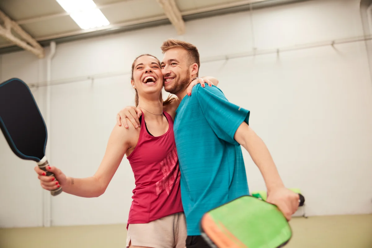 A young couple hugging on the pickleball court