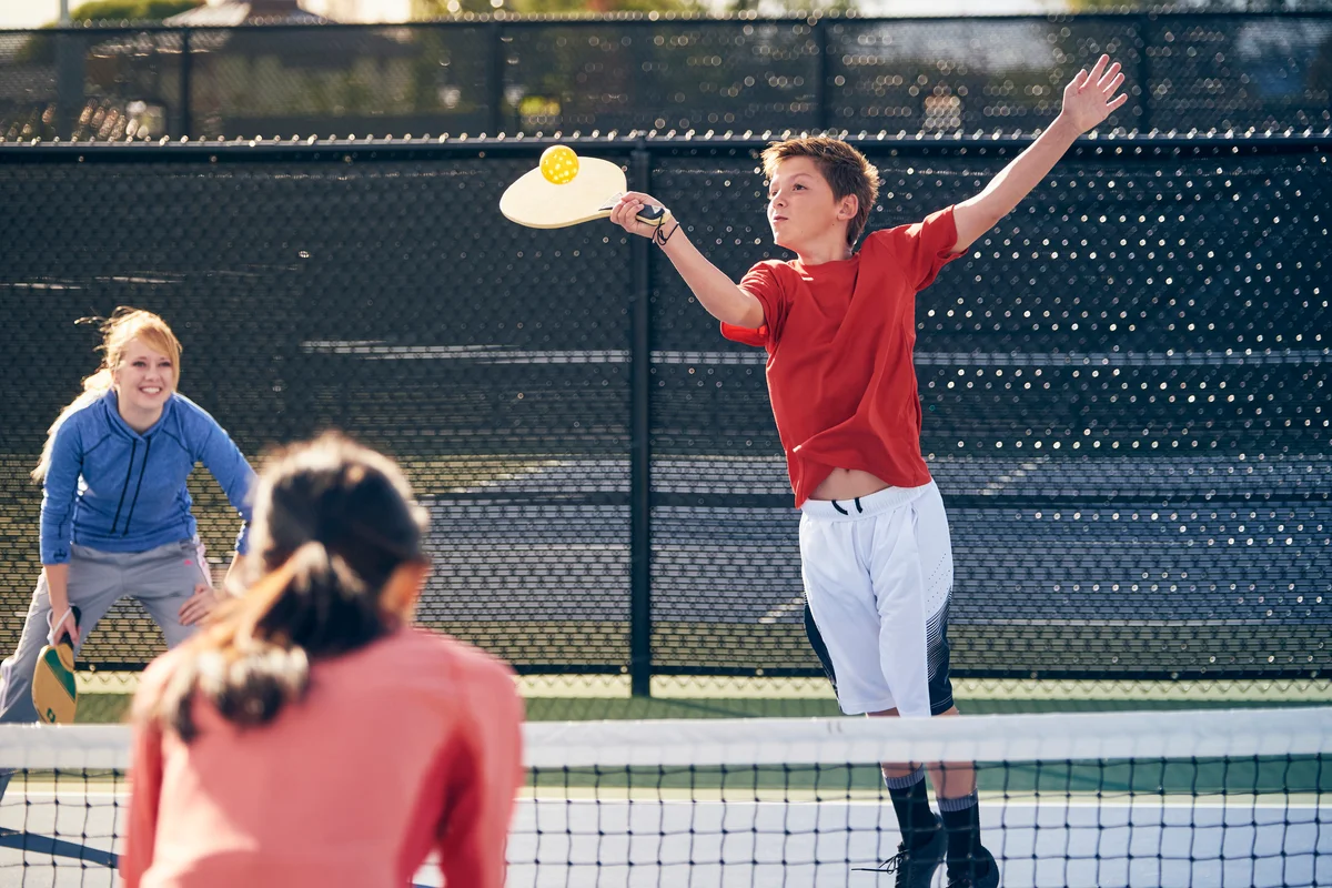 Young boy playing pickleball with family
