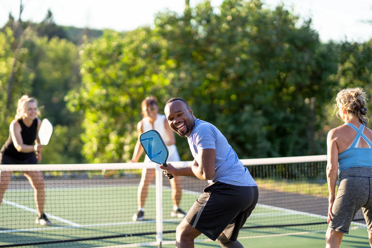Man smiling at camera while he plays pickleball
