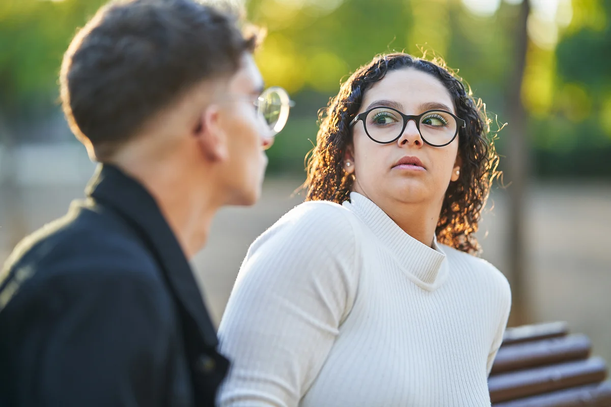 Woman keeping distance and rejecting a man while having a date together in a park