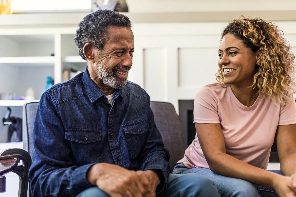 Senior man and adult daughter talking on couch