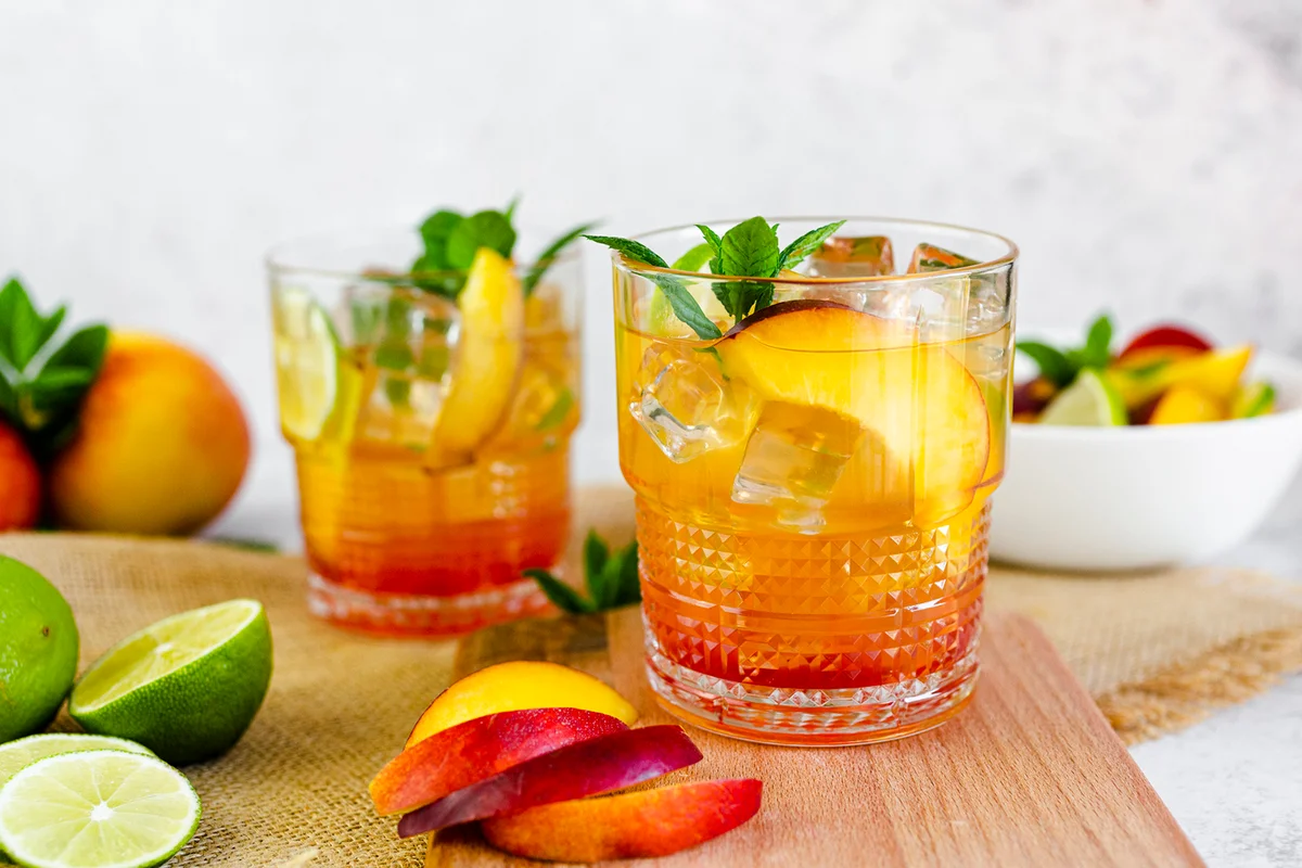 Cocktail with peach, mint and lime and ice cubes