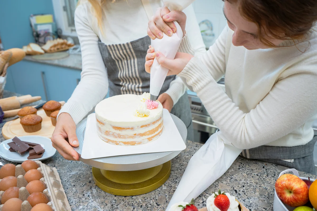 Girls decorating whipped cream on the cake