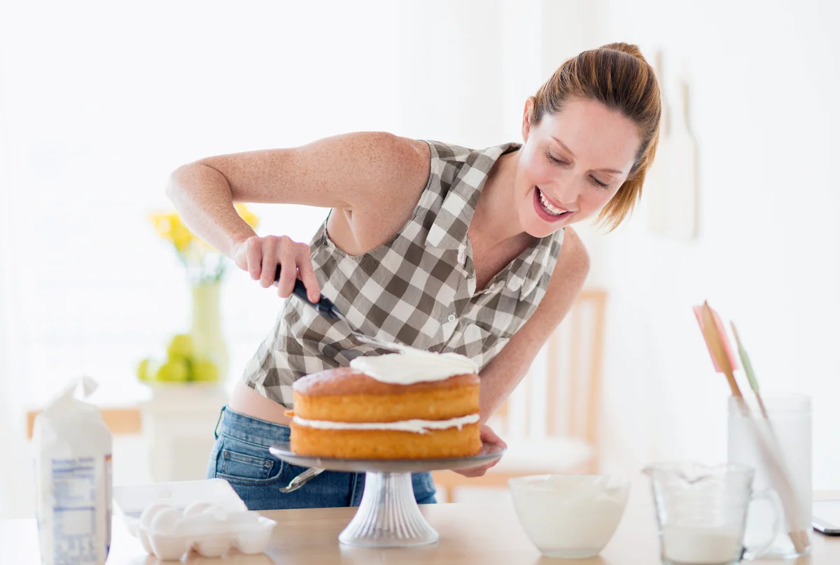 Woman decorating cake in kitchen