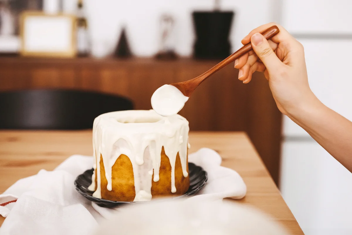 Woman's hand decorating cake with white chocolate