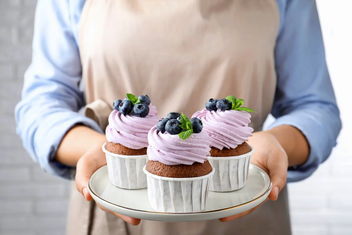 Woman holding plate with sweet cupcakes