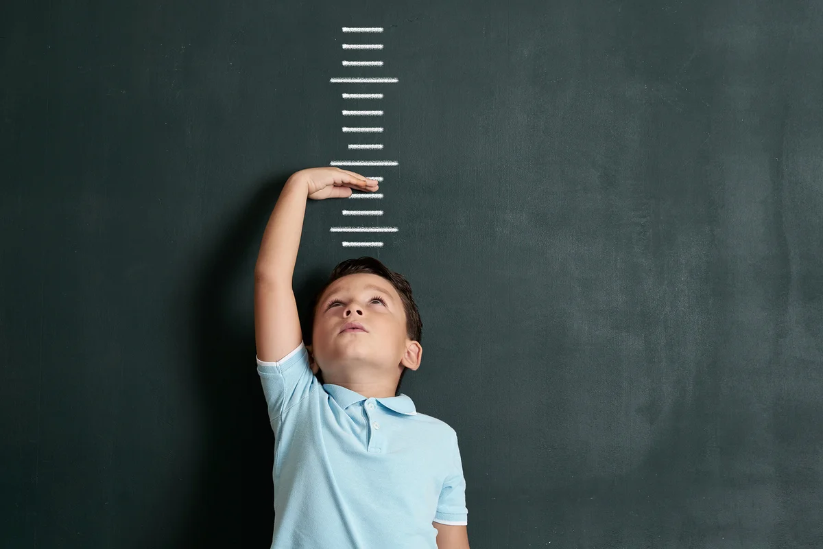Child measuring his height on wall.