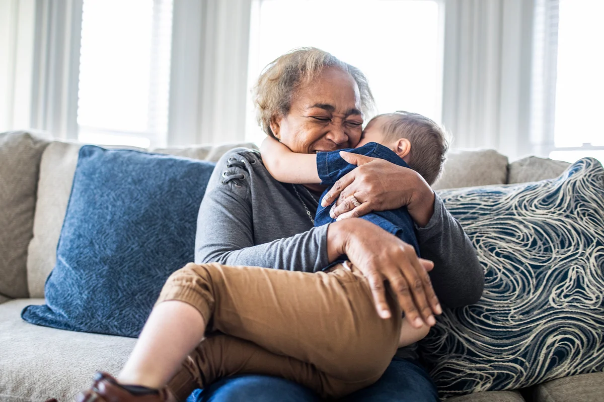 Grandmother embracing toddler grandson and laughing