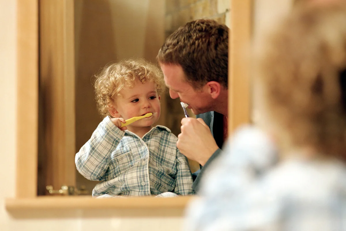 Father brushing teeth with son