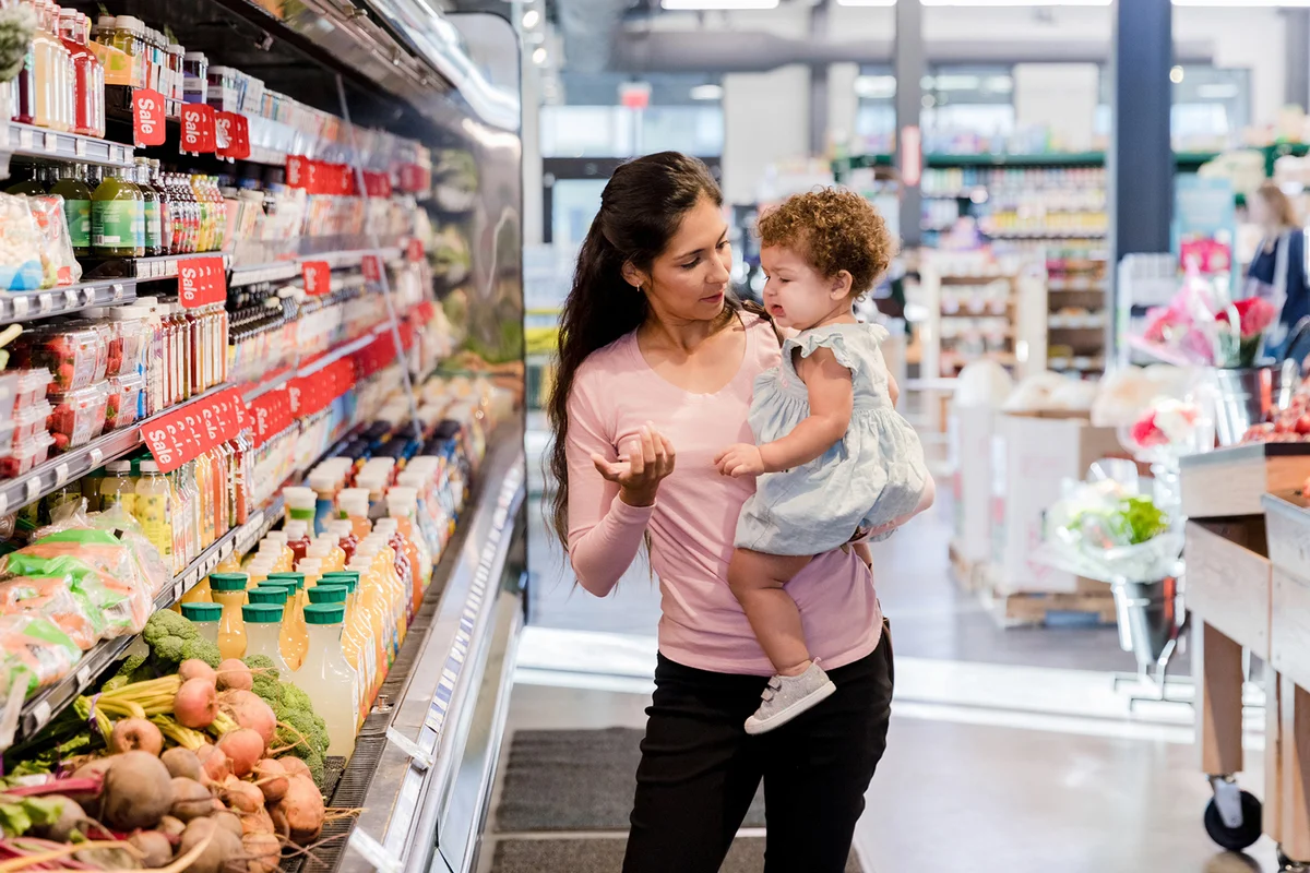Mid adult mom reasons with crying baby in grocery store