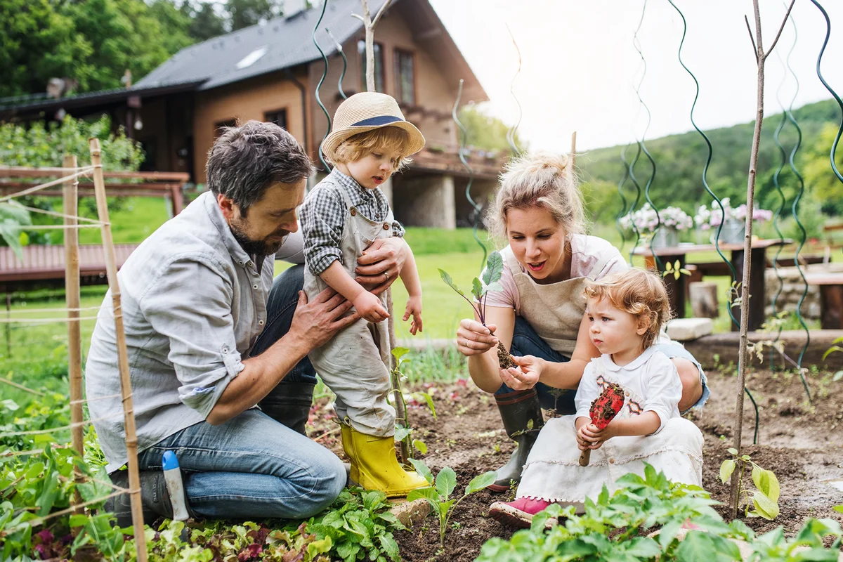 A portrait of cheerful family with two small children outdoors gardening