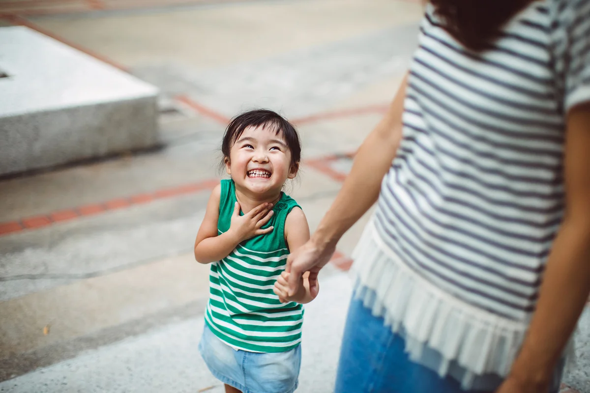 Smiling toddler holding hands with mom in park