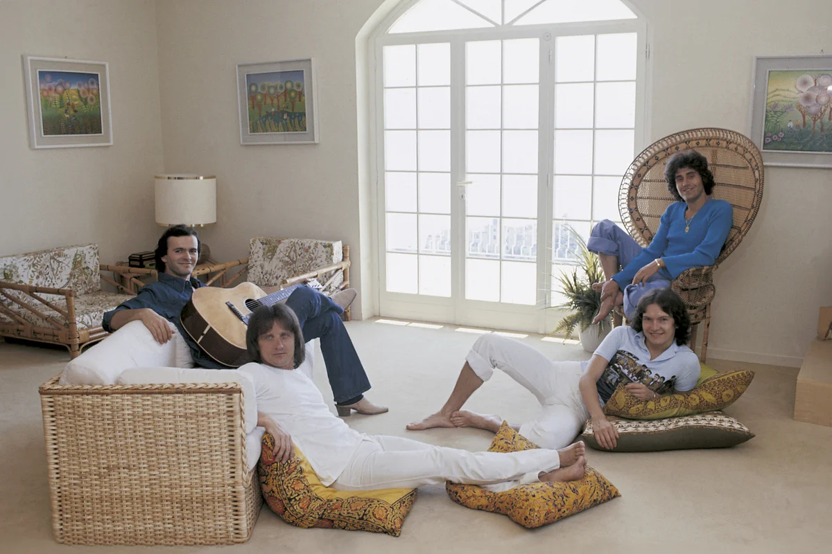 Italian band Pooh relaxing seated in a white livingroom among pillows and wicker sofas