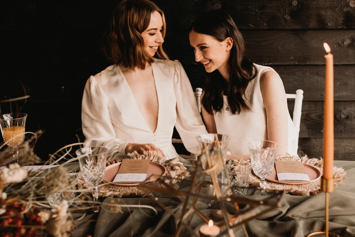 Two women on their wedding day at the head table decorated in boho style