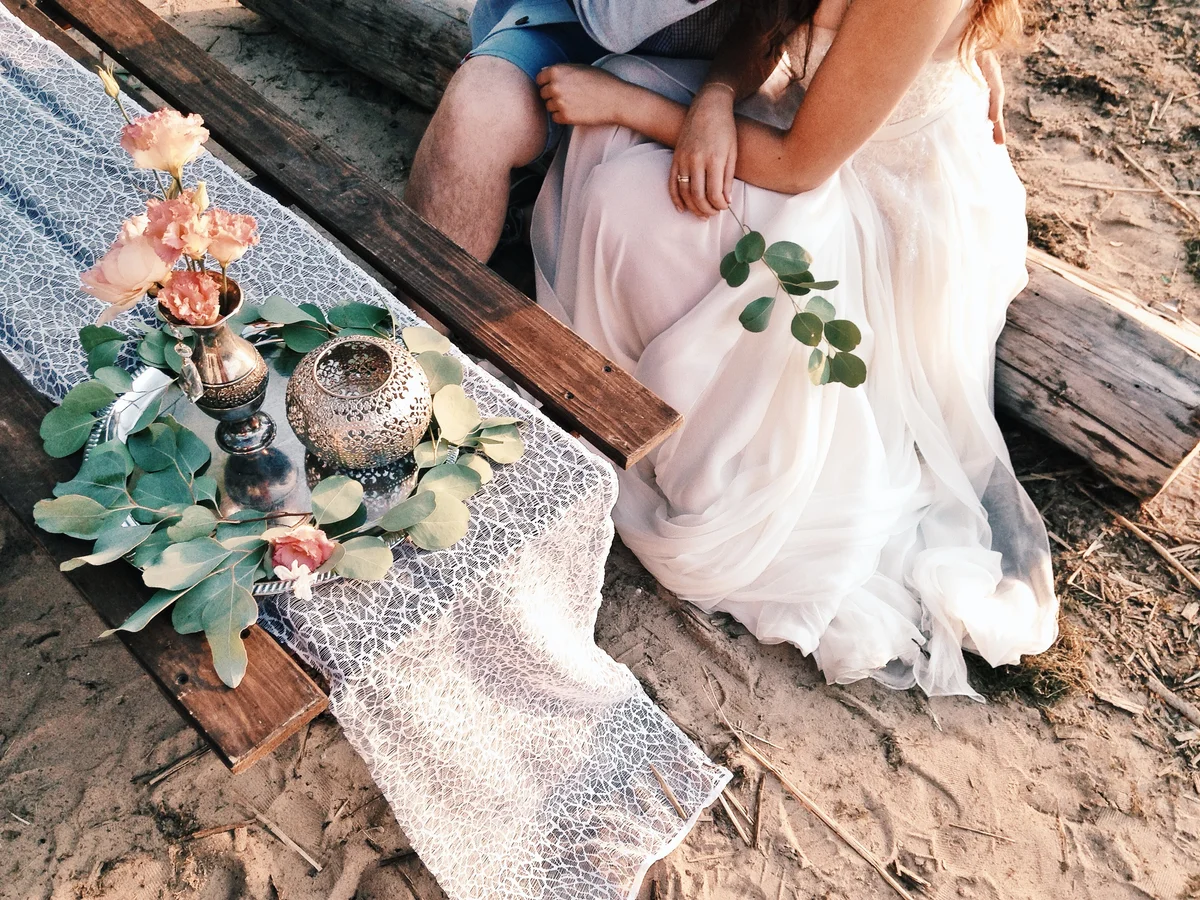 Wedding couple holding hands at rustic beach wedding setup